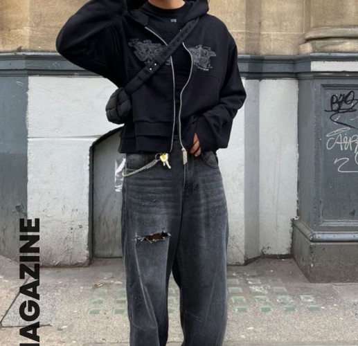A young man wearing Y2K fashion — baggy wide-leg jeans, a bold graphic tee, and chunky Nike sneakers on a city street in 2025