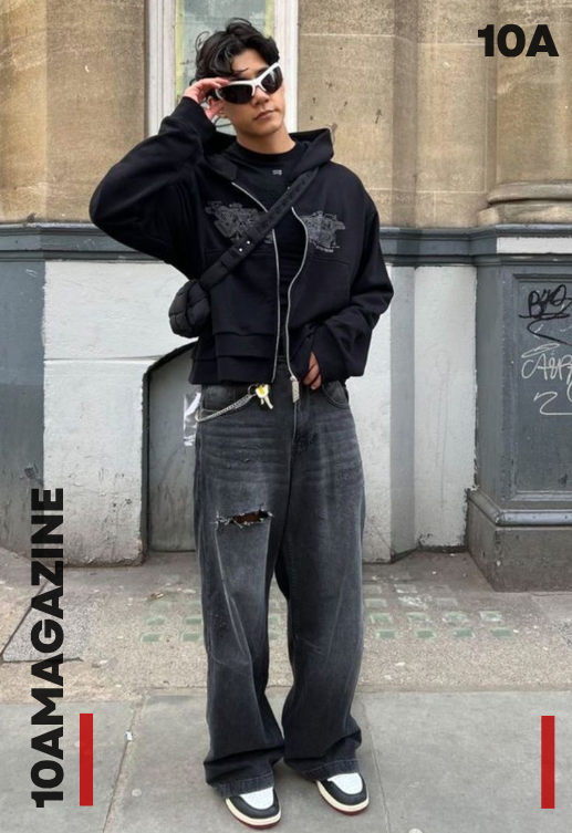 A young man wearing Y2K fashion — baggy wide-leg jeans, a bold graphic tee, and chunky Nike sneakers on a city street in 2025